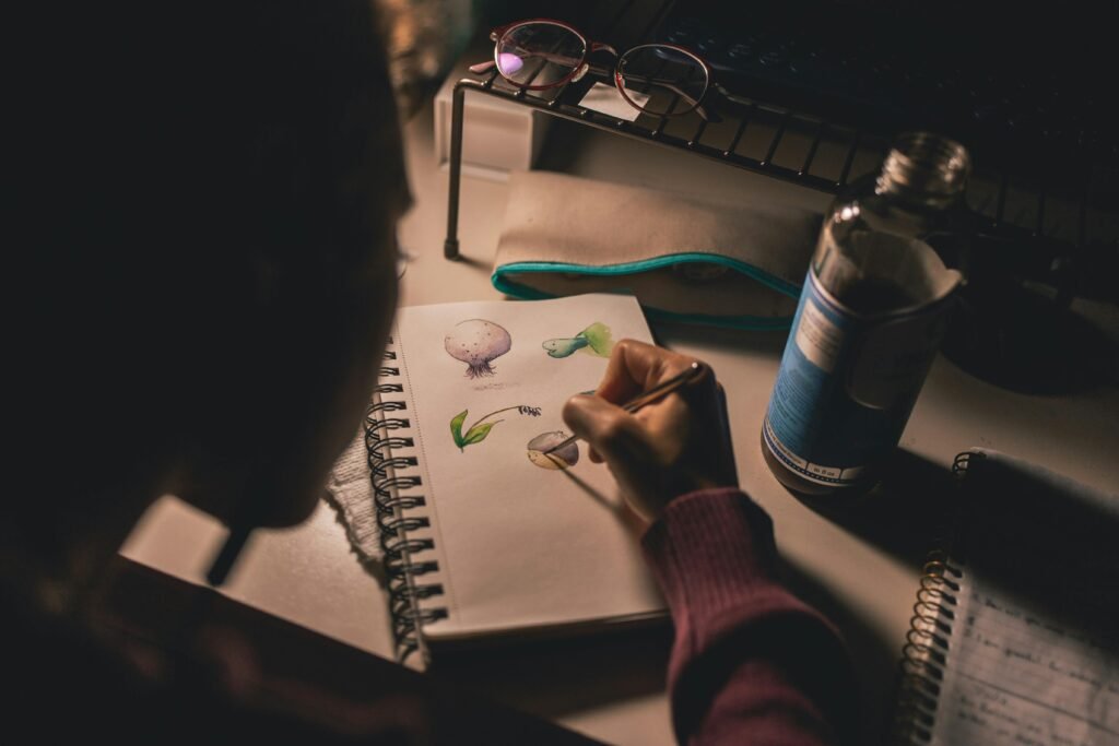 An artist sketches on a notebook under soft lighting, focusing on creativity and inspiration.